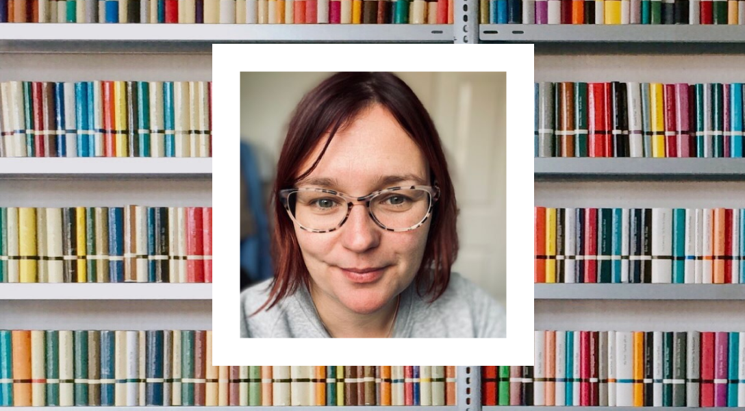 A close-up photo of a woman with short brown hair and glasses, smiling slightly at the camera. The photo is framed in a polaroid-style white border. The background behind the polaroid shows rows of colorful books on shelves.