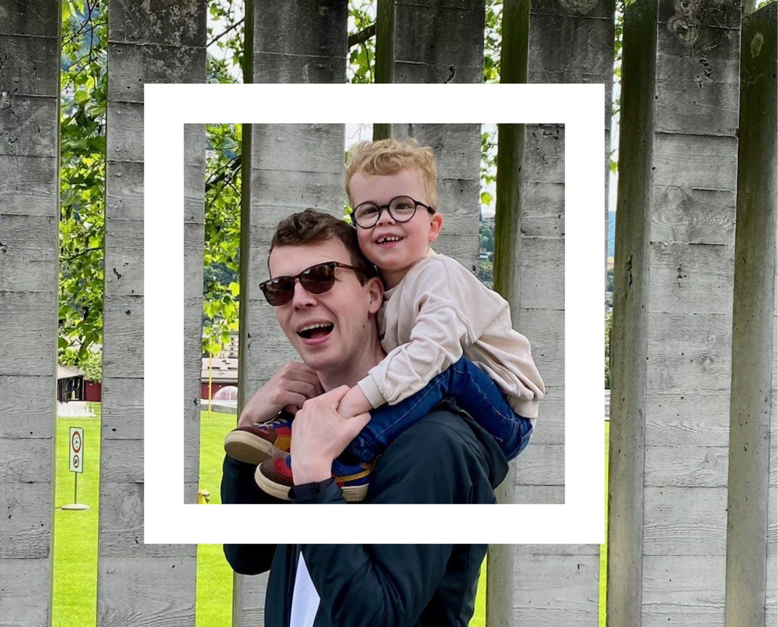  Two people sharing a joyful moment, laughing together. They are outdoors, with greenery in the background, and their expressions are filled with happiness and innocence. In the background, a man is giving a child a piggyback ride, adding to the playful atmosphere. 