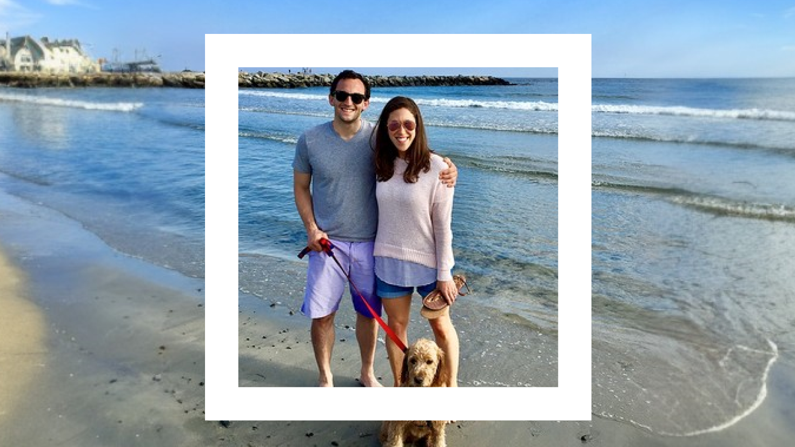 A Polaroid-style photograph features a couple standing on a sandy beach with gentle waves in the background. The man, wearing a grey t-shirt and purple shorts, has his arm around the woman, who is wearing a light pink sweater and denim shorts. They are both smiling and wearing sunglasses. The man is holding a leash attached to a brown dog sitting at their feet. The beach scene includes a rocky jetty and houses visible in the distance under a clear blue sky, creating a serene and cheerful atmosphere.