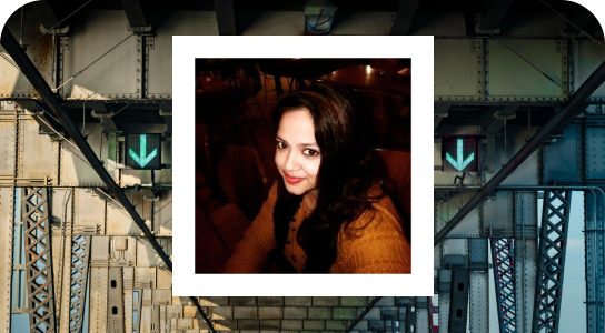 Priya chowdhury, senior data scientist in London,with dark colored hair, smiling directly in the front camera with a dark colored background, her photo is inside a white bordered frame set against a background of a bridge.